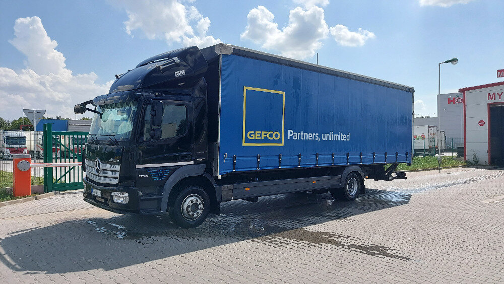 Tmavě modrý nákladní vůz Mercedes-Benz s plachtovou nástavbou