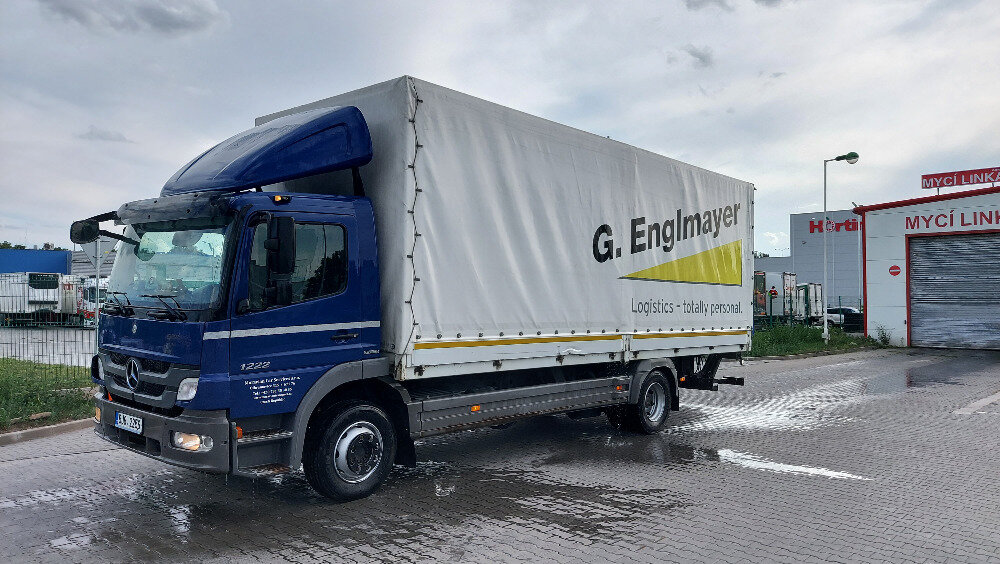 Modrý nákladní vůz Mercedes-Benz Atego s plachtovou nástavbou