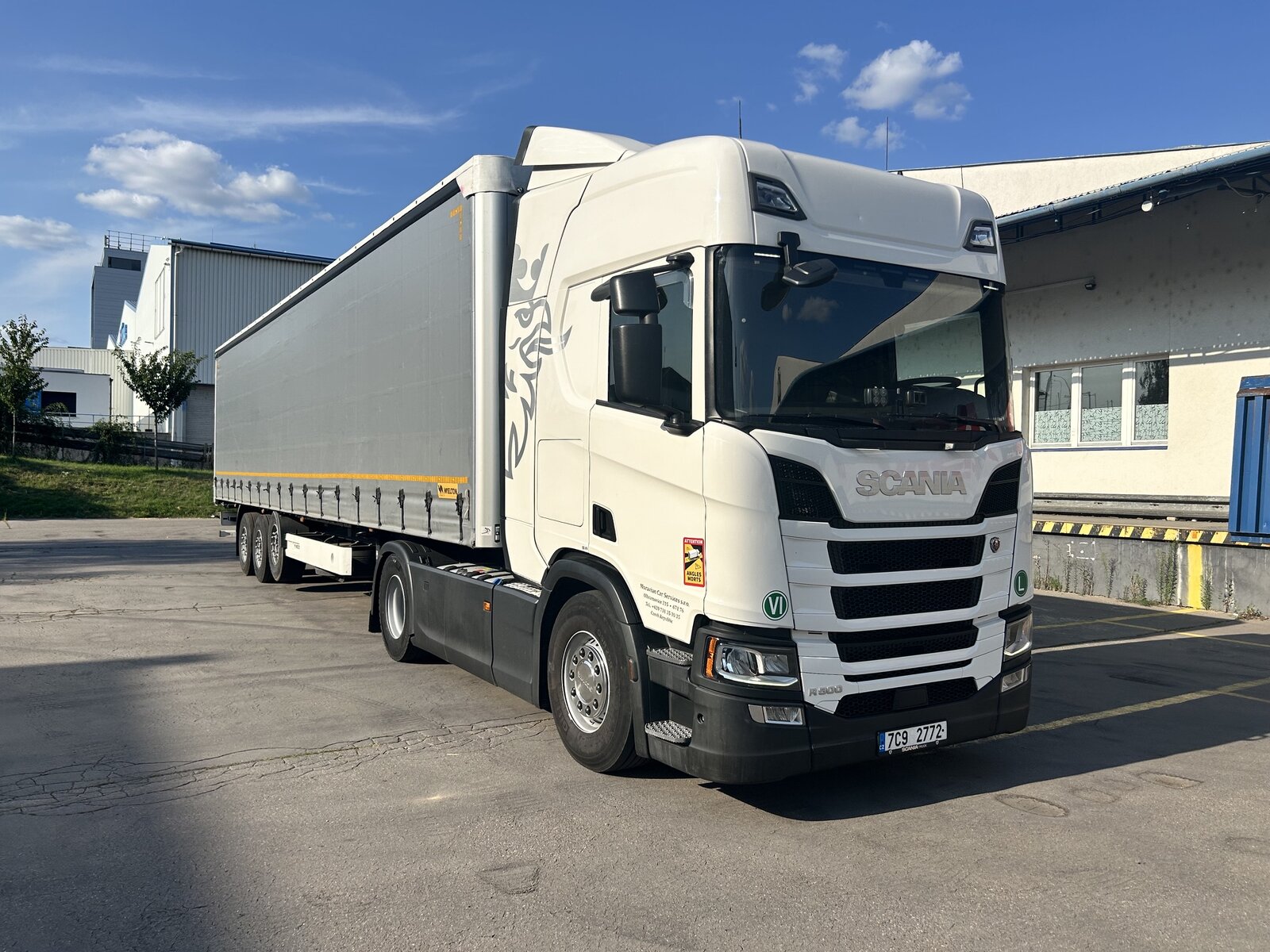 Bílý tahač Scania s plachtovým návěsem společnosti Moravian car services