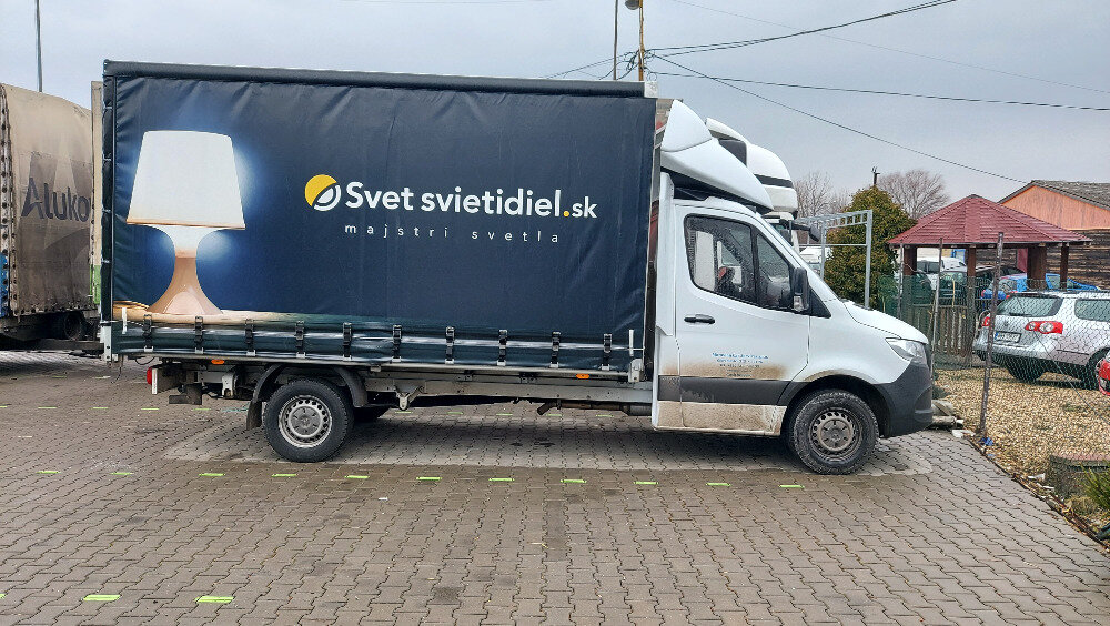 Bílá dodávka s plachtovým přívěsem